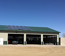 Solar panels attached to a green metal roof with parking bays below